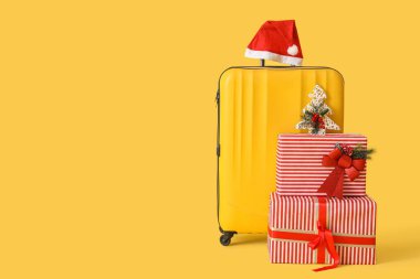 Sarı arka planda Noel Baba şapkalı ve Noel hediyeli çanta.