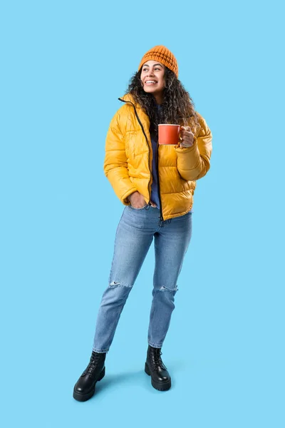 stock image Happy young African-American woman with cup of hot mulled wine on blue background