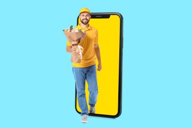 Çiçek buketi olan erkek kurye ve açık mavi arka planda büyük akıllı telefon.