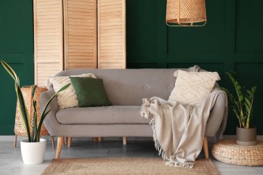 Interior of living room with grey sofa, houseplants and folding screen