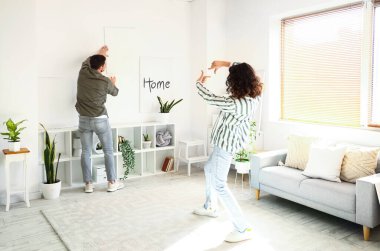Evdeki ışık duvarına resim asan genç bir çift.