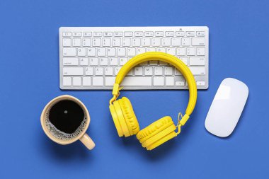 Modern kulaklıklar, kahve fincanı, bilgisayar faresi ve klavye.