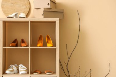 Butikte bej duvarın yanında farklı şık ayakkabıları olan raf ünitesi.