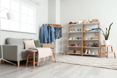 Rafların, kanepenin, rafın, rafın, şık kıyafetlerin ve ayakkabıların olduğu aydınlık butiğin içi.