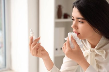 Ofisinde burun damlası olan hasta bir kadın var.