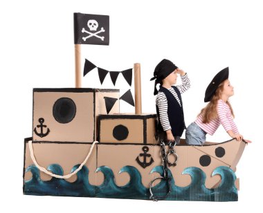 Beyaz arka planda karton gemide oynayan sevimli küçük korsanlar.