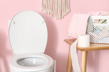 Renkli duvarın yanında rulo kağıt, çamaşır ve klozet olan masa.