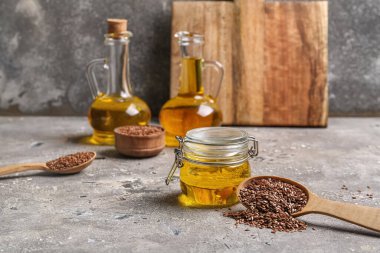 Cam kavanoz keten yağı ve arkaplanda tohumlar.