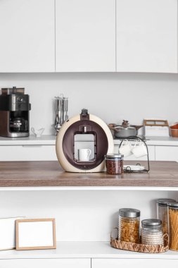 Mutfaktaki masada kavrulmuş fasulye ve fincanla modern kahve makinesi.