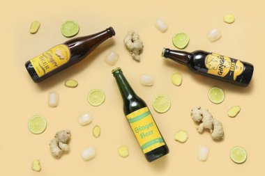 Bej arka planda taze zencefilli bira, limon dilimleri ve buz küpleriyle kompozisyon