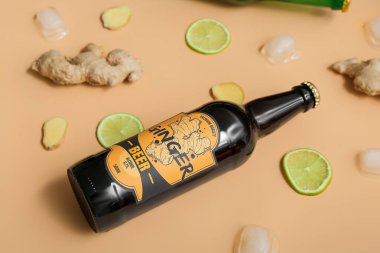 Bej arka planda taze zencefilli bira, limon dilimleri ve buz küpleriyle kompozisyon, yakın plan.