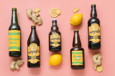 Farklı şişelerde zencefilli bira ve pembe arka planda limonlu kompozisyon.