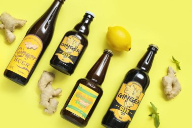 Farklı zencefilli bira, limon ve nane içeren kompozisyon sarı arka planda.