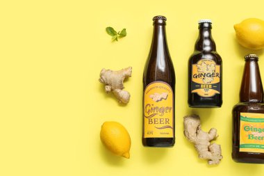 Farklı zencefilli bira, limon ve nane içeren kompozisyon sarı arka planda.