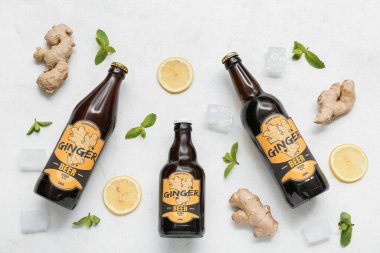 Beyaz zemin üzerinde taze zencefilli bira, nane, limon dilimleri ve buz küpleri olan kompozisyon