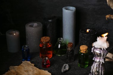 Cadıların sihirli özellikleri, mumlar ve karanlık masa üzerindeki zehir şişeleri.