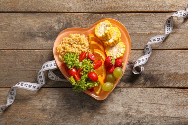 Taze sağlıklı ürünlerle dolu tabaklar ve ahşap arka planda mezura. Diyet kavramı