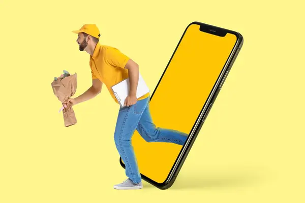 Running male courier with bouquet of flowers and big smartphone on yellow background