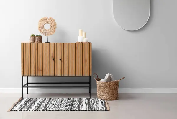 Stylish wooden cabinet near white wall
