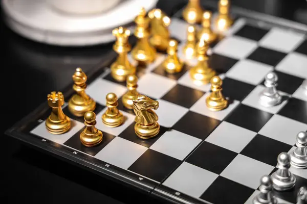 Golden and silver chess pieces on game board, closeup