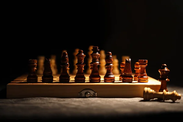 Game board with wooden chess pieces on dark background, closeup