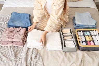 Yatak odasında kadın elbiselerini sınıflandırıyor.