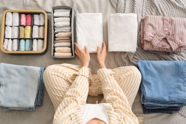 Yatak odasında kadın elbiselerini sınıflandırıyor.