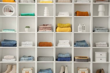 Farklı giysi ve dekorlarla dolu beyaz raf ünitesi