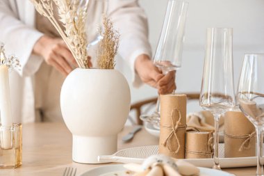 Yemek odasında kurumuş çiçeklerle masa hazırlayan kadın, yakın plan.