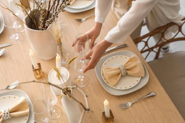Kadın elleri yemek odasında masayı hazırlıyor, yakın plan.