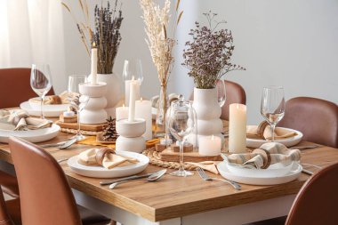 Kurumuş çiçekleri, yanan mumları ve kozalakları olan zarif bir masa.