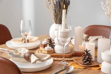 Kurumuş çiçekleri, yanan mumları ve kozalakları olan zarif bir masa.