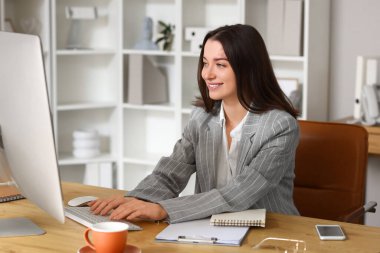 Ofiste bilgisayarla çalışan genç bir iş kadını.