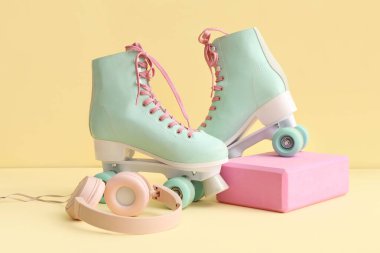 Sarı arka planda patenler ve kulaklıklar.