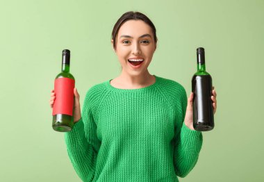 Yeşil arka planda şarap şişeleri olan güzel genç bir kadın.