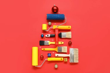 Ressamın aletlerinden yapılmış Noel ağacı ve kırmızı arka plandaki süslemeler