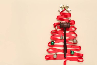 Kırmızı kurdeleden yapılmış Noel ağacı, yargıç tokmağı ve renk arkaplanındaki süslemeler