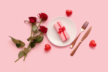 Hediye kutusu, kırmızı güller ve pembe arka planda kalpler olan güzel bir masa. Sevgililer Günü kutlaması