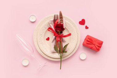 Kırmızı gül, hediye kutusu ve pembe arka planda yanan mumlarla güzel bir masa. Sevgililer Günü kutlaması