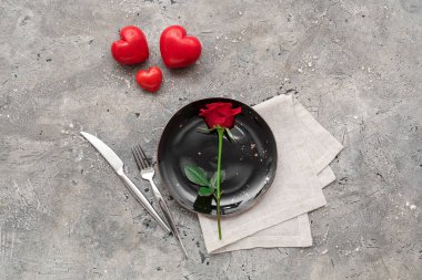 Kırmızı gül ve gri arka planda dekoratif kalplerle güzel bir masa. Sevgililer Günü kutlaması