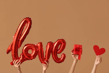 Hava balonlu kadın elleri. Aşk kelimesi şeklinde. Hediye kutusu ve kahverengi arka planda kağıt kalp. Sevgililer Günü kutlaması