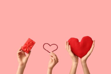 Kumaş kalpli kadın eller ve pembe arka planda hediye kutusu. Sevgililer Günü kutlaması