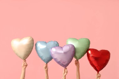 Pembe arka planda kalp şeklinde hava balonları olan kadın eller. Sevgililer Günü kutlaması