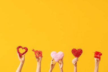 Farklı kalpleri olan kadın elleri ve sarı arka planda hediye kutusu. Sevgililer Günü kutlaması
