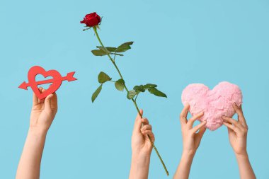 Kırmızı gül, dekoratif ve mavi arka planda kumaş kalpli kadın elleri. Sevgililer Günü kutlaması