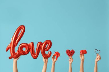 Kelime şeklinde balonları olan kadın elleri. Aşk, dekoratif kalpler ve mavi arka planda hediye kutuları. Sevgililer Günü kutlaması