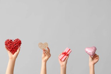 Farklı kalpleri olan kadın elleri ve gri arka planda hediye kutusu. Sevgililer Günü kutlaması