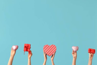 Kalp şeklinde balonları ve mavi arka planda hediye kutuları olan kadın elleri. Sevgililer Günü kutlaması