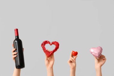 Farklı kalpleri olan kadın elleri ve gri arka planda bir şişe şarap. Sevgililer Günü kutlaması