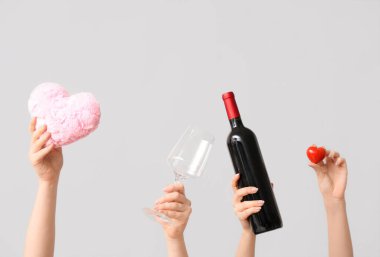 Kumaş kalpli kadın eller, gri arka planda cam ve şarap şişesi. Sevgililer Günü kutlaması